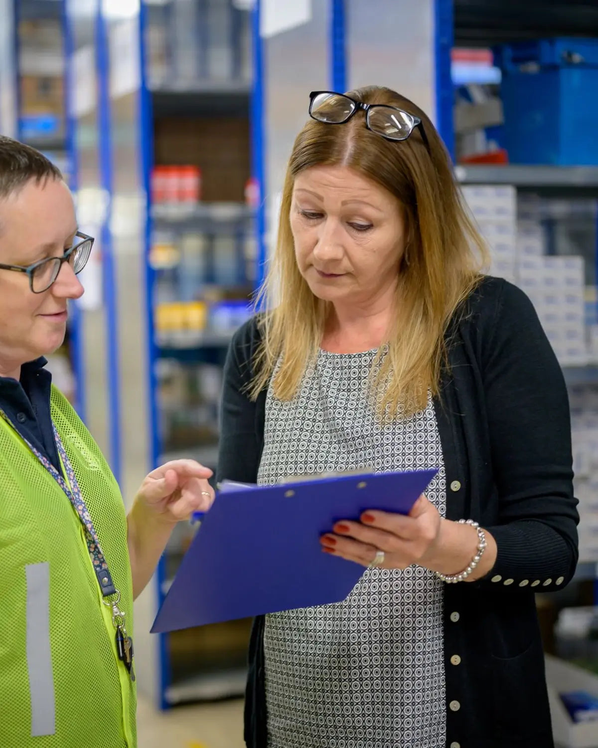Two people reviewing a clipboard inside a warehouse